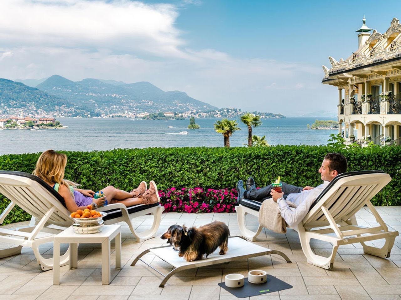 Couple relaxing with their dog on a hotel terrace by the lake