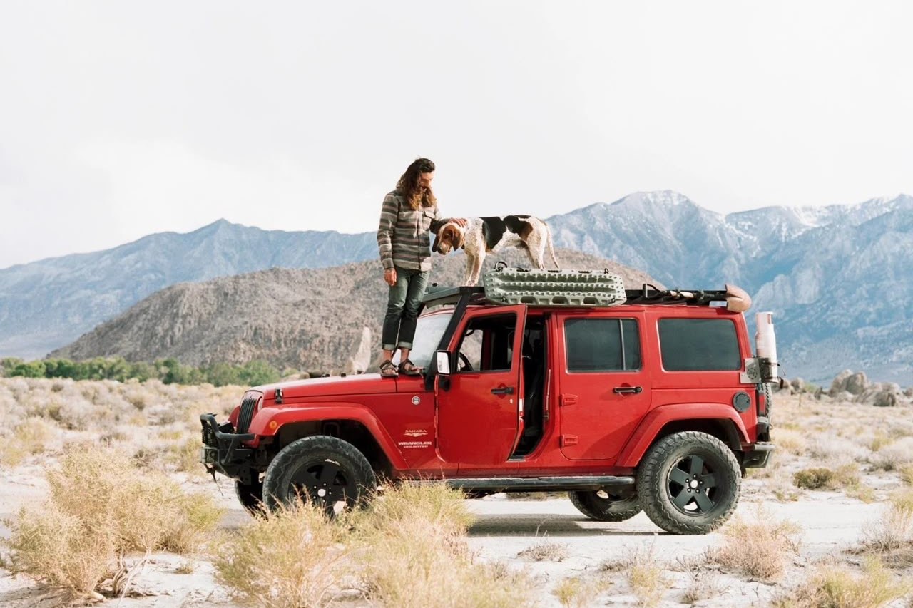 Owner and dog with a red 4x4 in the mountains