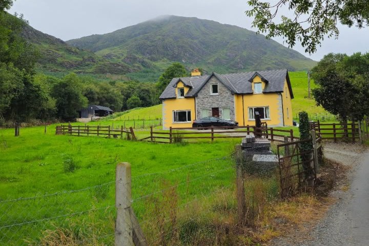 Yellow farmhouse below a misty mountain