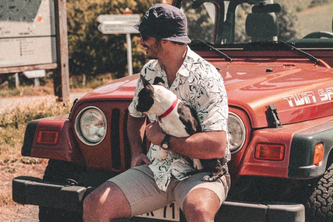 Owner and dog on a jeep bonnet on a mountain road trip